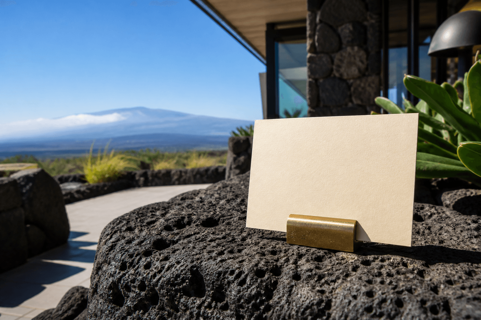 A Kohala lava-stone counter with a west-side corridor card, hard sun, Mauna Kea faint.