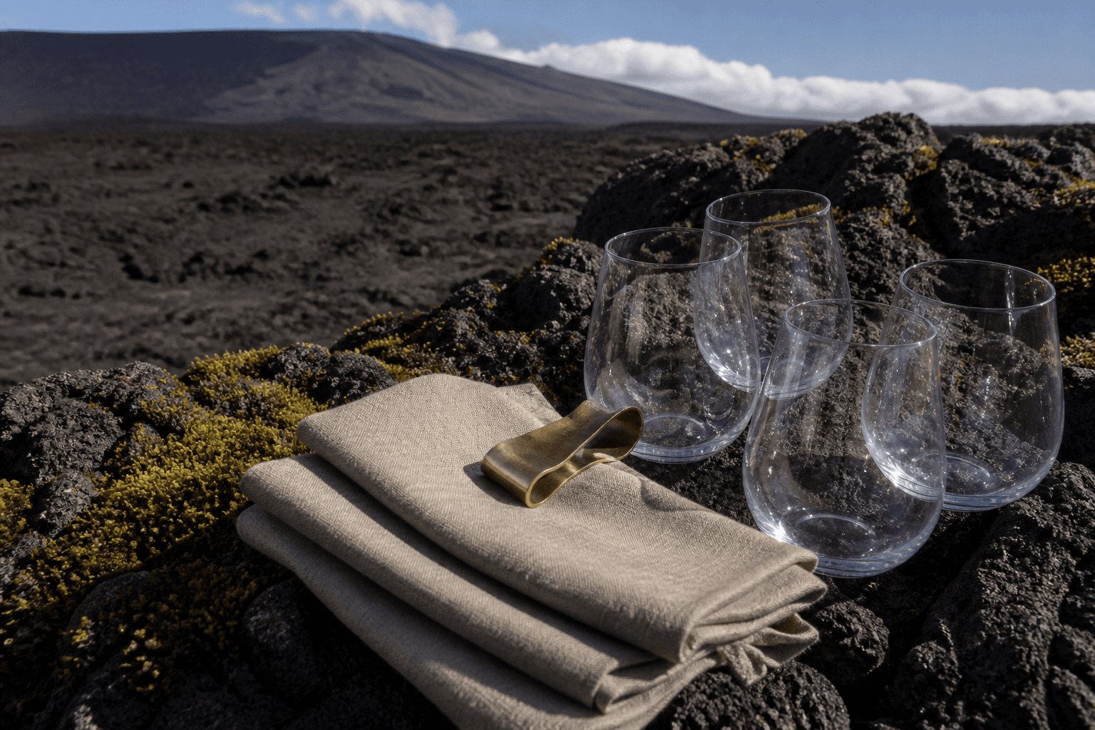 Unused empty glasses and sand linen on a Kohala lava-stone pass in hard sun.