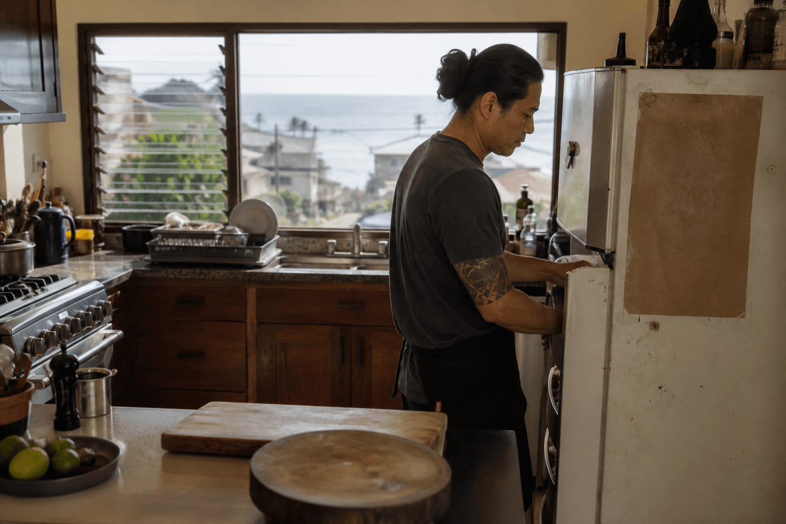 A Kona town household kitchen on a weekday — used fridge, coffee slopes, not a resort villa.